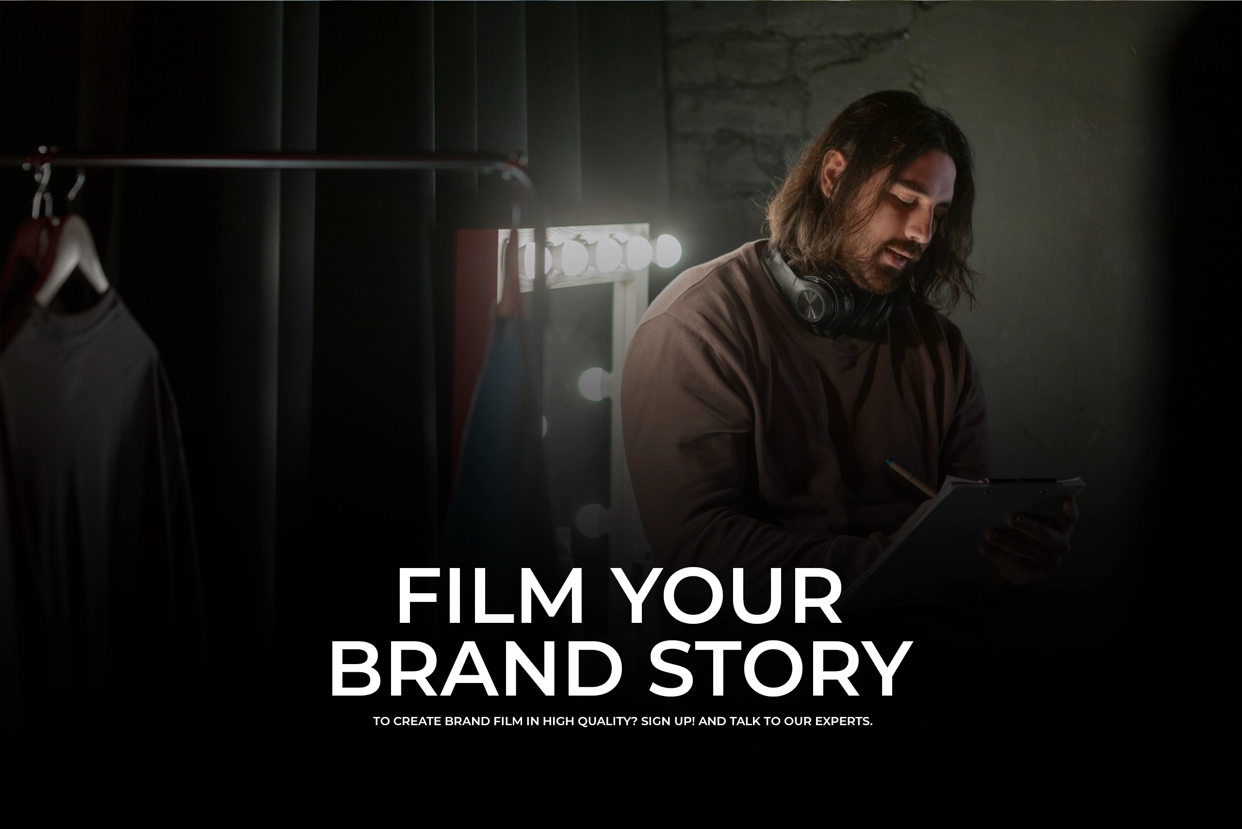 A cinematic shot of a film crew in an office setting, with a large professional video camera in the foreground and a woman focused on the production in the background. Text overlay reads "FILM YOUR BUSINESS."