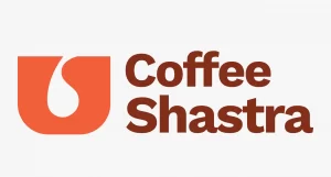 A minimalist logo for Coffee Shastra featuring an orange "U" shaped icon with a white coffee drop cutout, positioned next to the brand name in bold brown typography.
